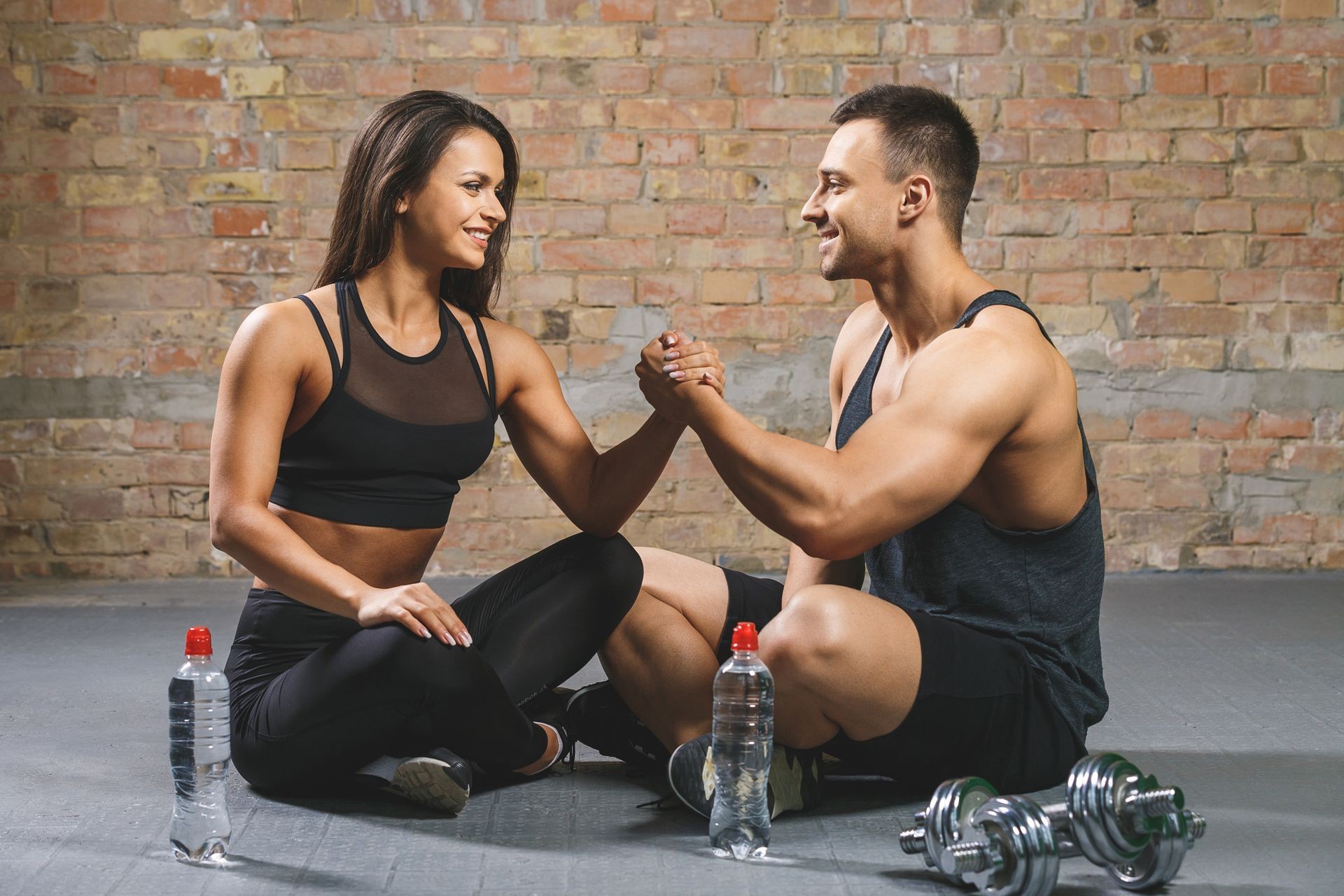 Fitness man and woman giving each other a high five after the training session in gym. Fit couple high five after workout in health club. Fitness man and woman giving each other a high five after the training session in gym. Fit couple high five after workout in health club.